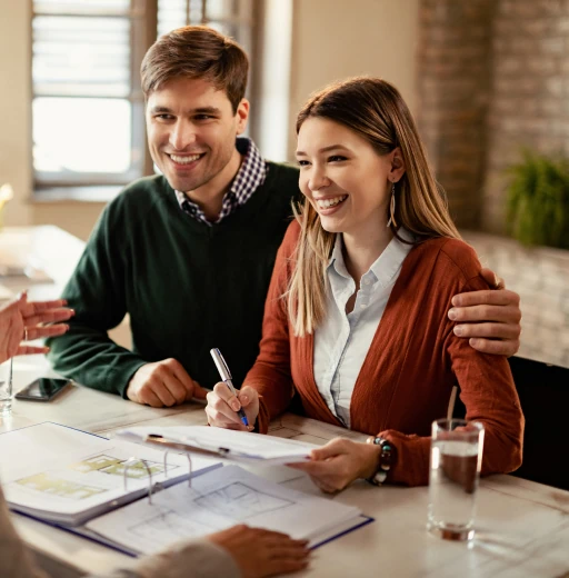 Pareja reunida con asesor inmobiliario revisando documentos de inversión